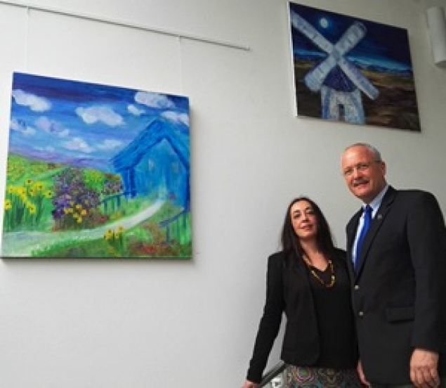 Die Künsterin Antonia Cantalejo u. Bürgermeister Manfred Helfrich vor zwei der Bilder im Rathaus-Foyer, die den Titel tragen „Das blaue Hau“ und „Die Mühle“.